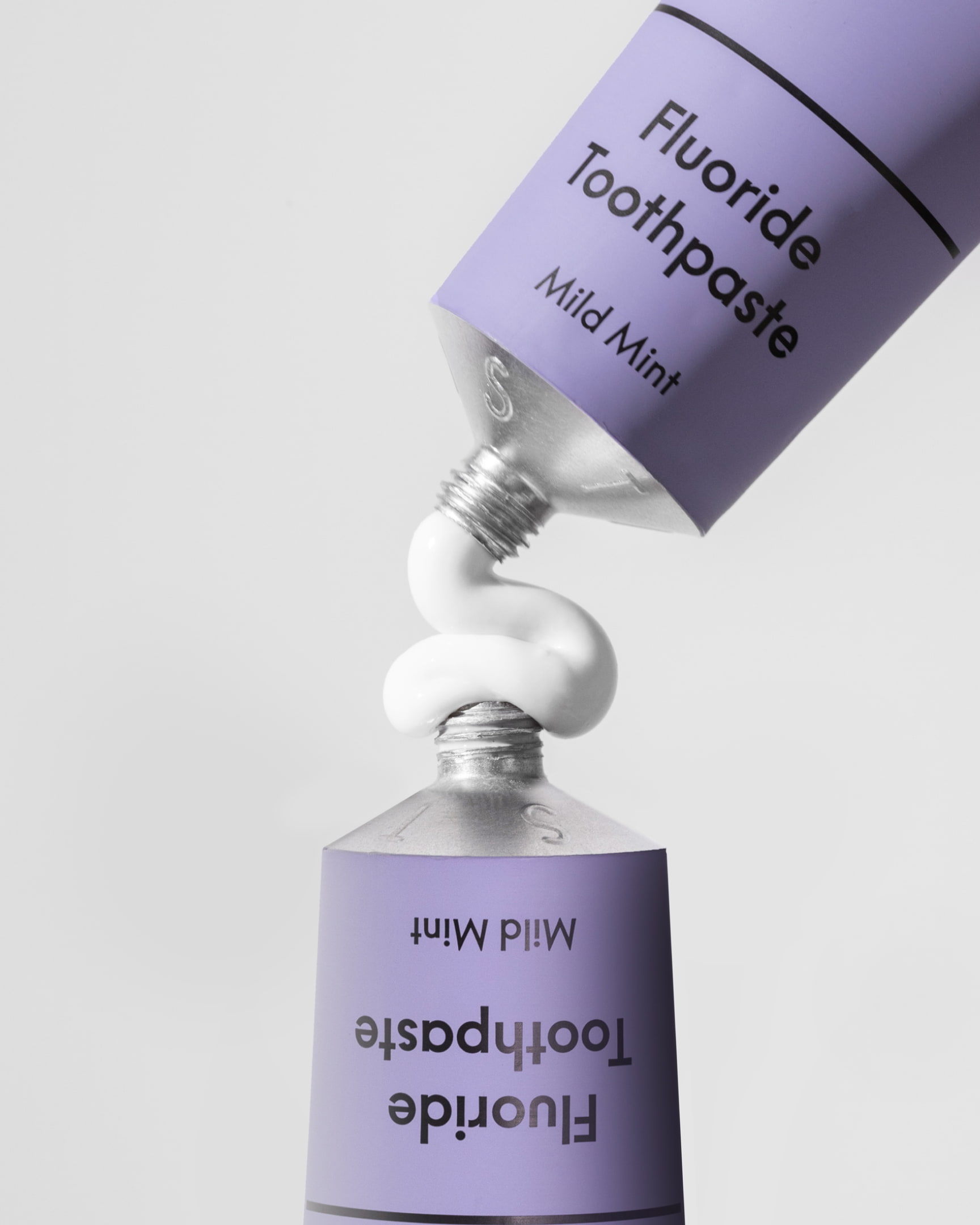 Two Times Elliott — Paist — two lilac PAIST Sensitive Mild Mint toothpaste tubes balanced cap-to-cap in a mirrored composition on a pale surface