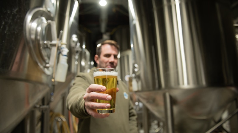 Sloop Brewing. Holding up pint of beer.