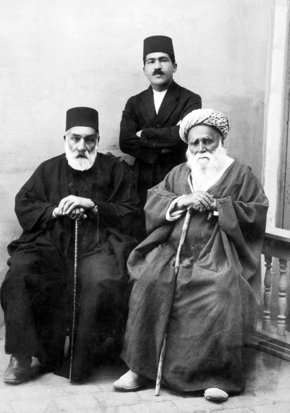 Hand of the Cause Hájí Amín (seated, right), Hakim Bashi (seated, left), Muhammad Labib (standing), early 1900s