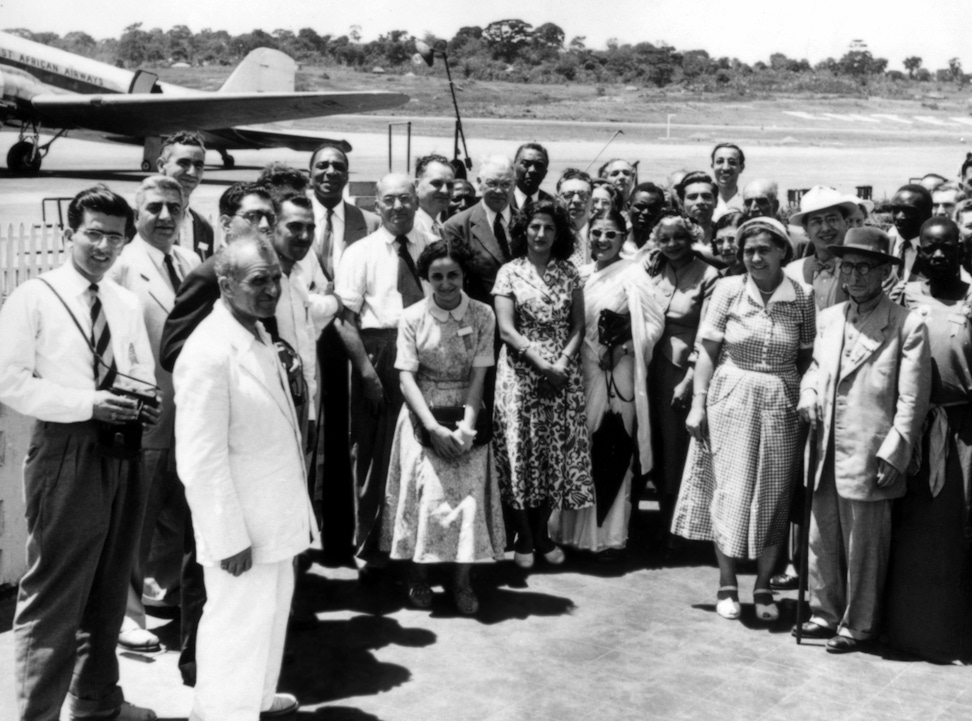 Elsie Austin (at right of woman carrying umbrella) in a group of Bahá’ís including Hands of the Cause Tarazu’llah Samandari (wearing dark hat at right), Leroy Ioas (wearing jacket and tie, center), Zikrullah Khadem (at left of Mr. Ioas), Ali-Akbar Furutan (wearing spectacles, at right of Mr. Ioas). Hasan Balyuzi, later appointed a Hand of the Cause is at center, rear. Kampala, Uganda. 1953