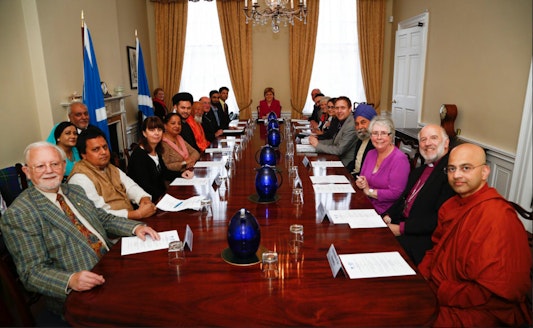 First Minister of Scotland Nicola Sturgeon sits at the head of a table at which gathered representatives of the country's religious groups, 8 September 2015 in Edinburgh. Baha'i representative Jeremy Fox is seated front left