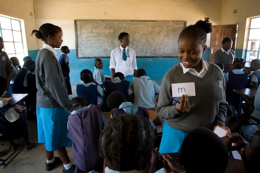 Students from Banani School (standing), a Bahá'í-inspired school in Chisamba, Zambia teach students at a nearby elementary school as part of a service project