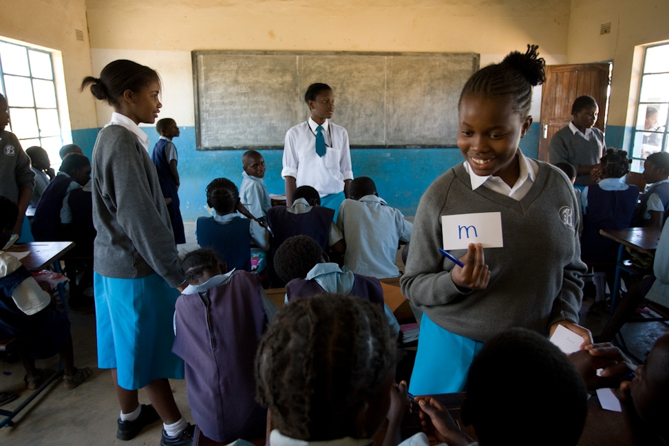 Students from Banani School (standing), a Bahá'í-inspired school in Chisamba, Zambia teach students at a nearby elementary school as part of a service project