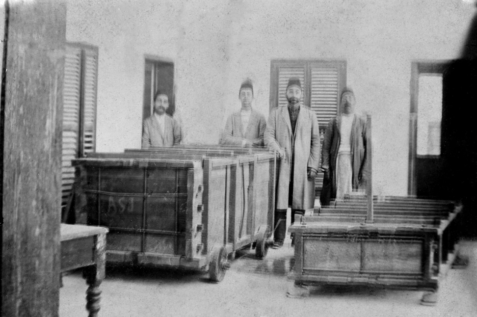 A crate containing the sarcophagus for the casket of the Báb in a house in Haifa some time before 1909. The identity of the Bahá’ís are unknown