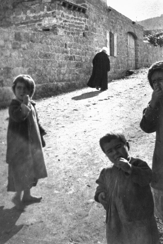 ‘Abdu’l-Bahá walking up Haparsim Street with three kids eating sweets that ‘Abdu’l-Bahá just gave them, c. 1920