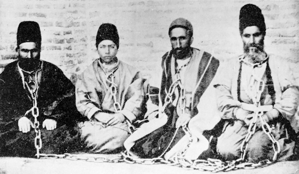 A Bahá’í father and son (at left) in chains after being arrested with fellow Bahá’ís, in a photograph taken around 1896. Both were subsequently executed