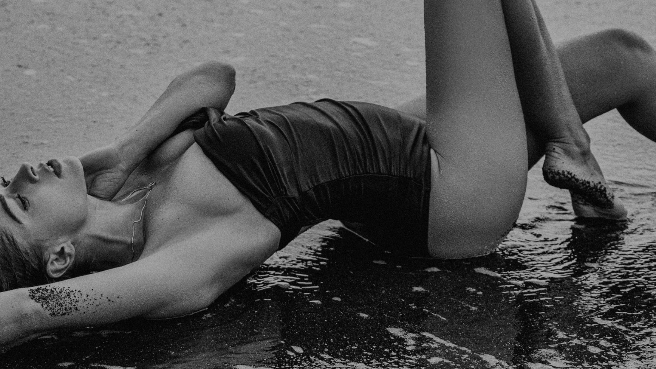 Woman in a bathing suit posing on the sand.