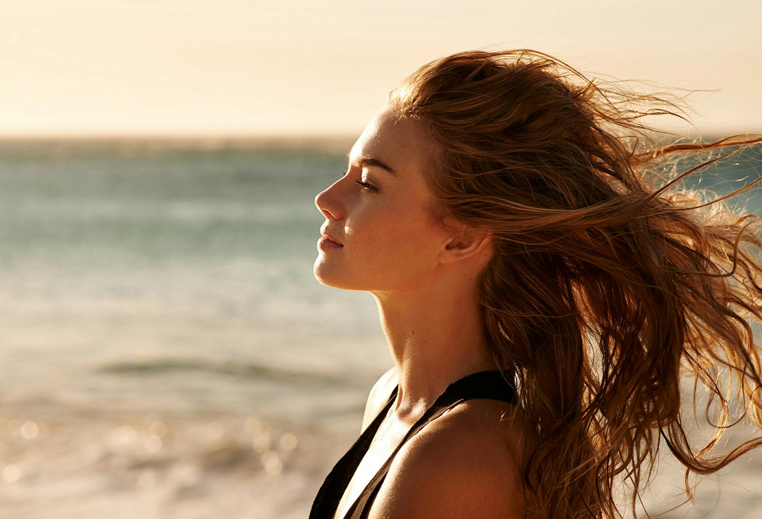 Woman Standing on the Beach with Wind Blowing Through Her Hair