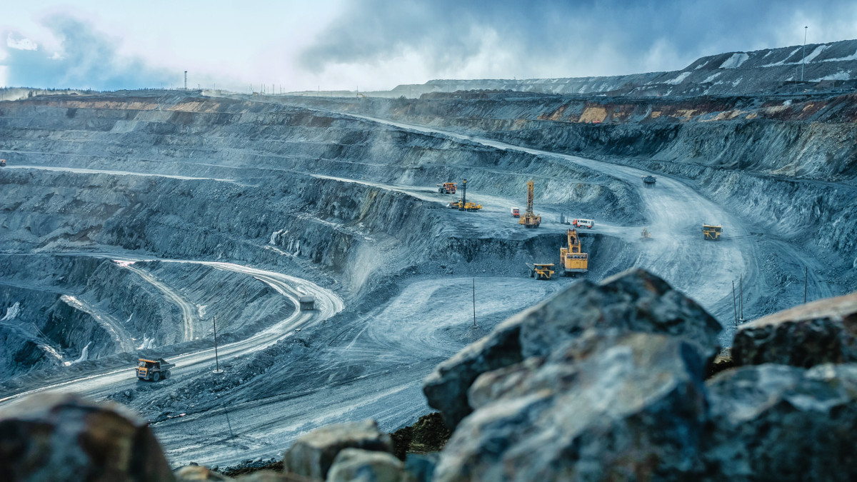Excavators and heavy trucks working in a large, open-cast mine