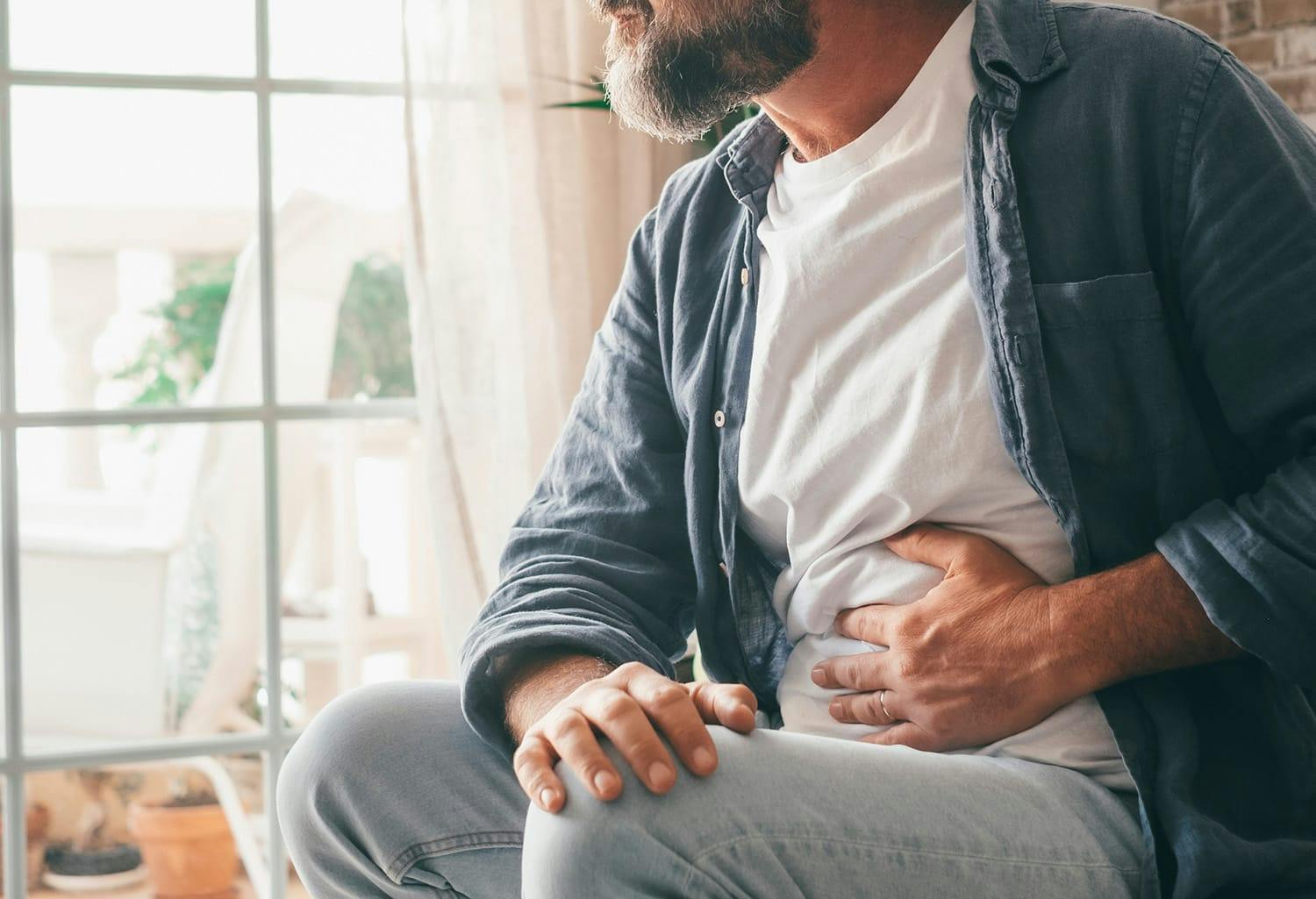Man sitting down holding his stomach