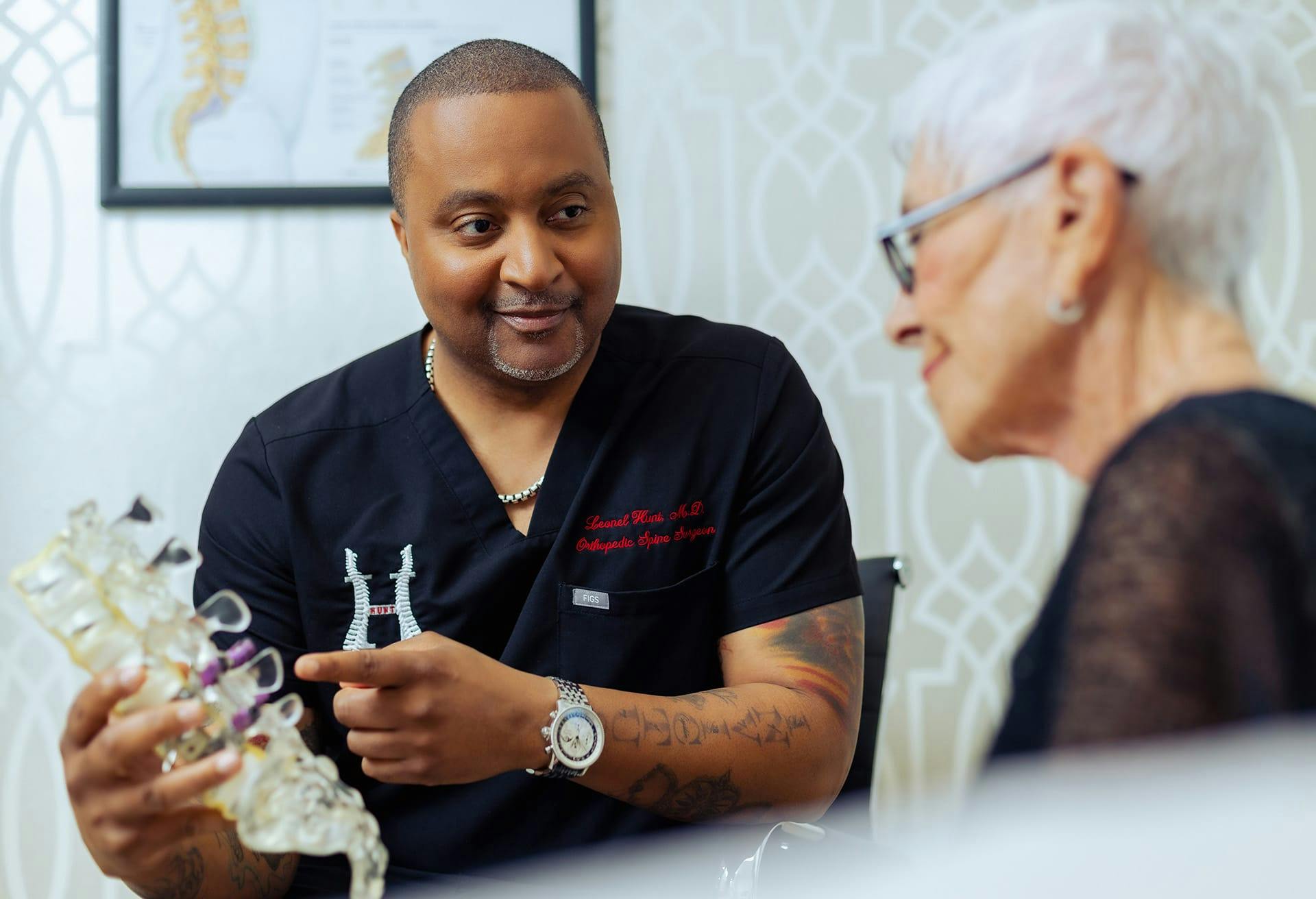 Dr. Leonel Hunt showing a patient a model of the spine
