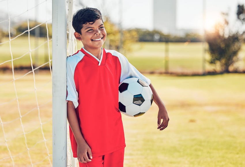 Kid with a soccer ball by a soccer goal post