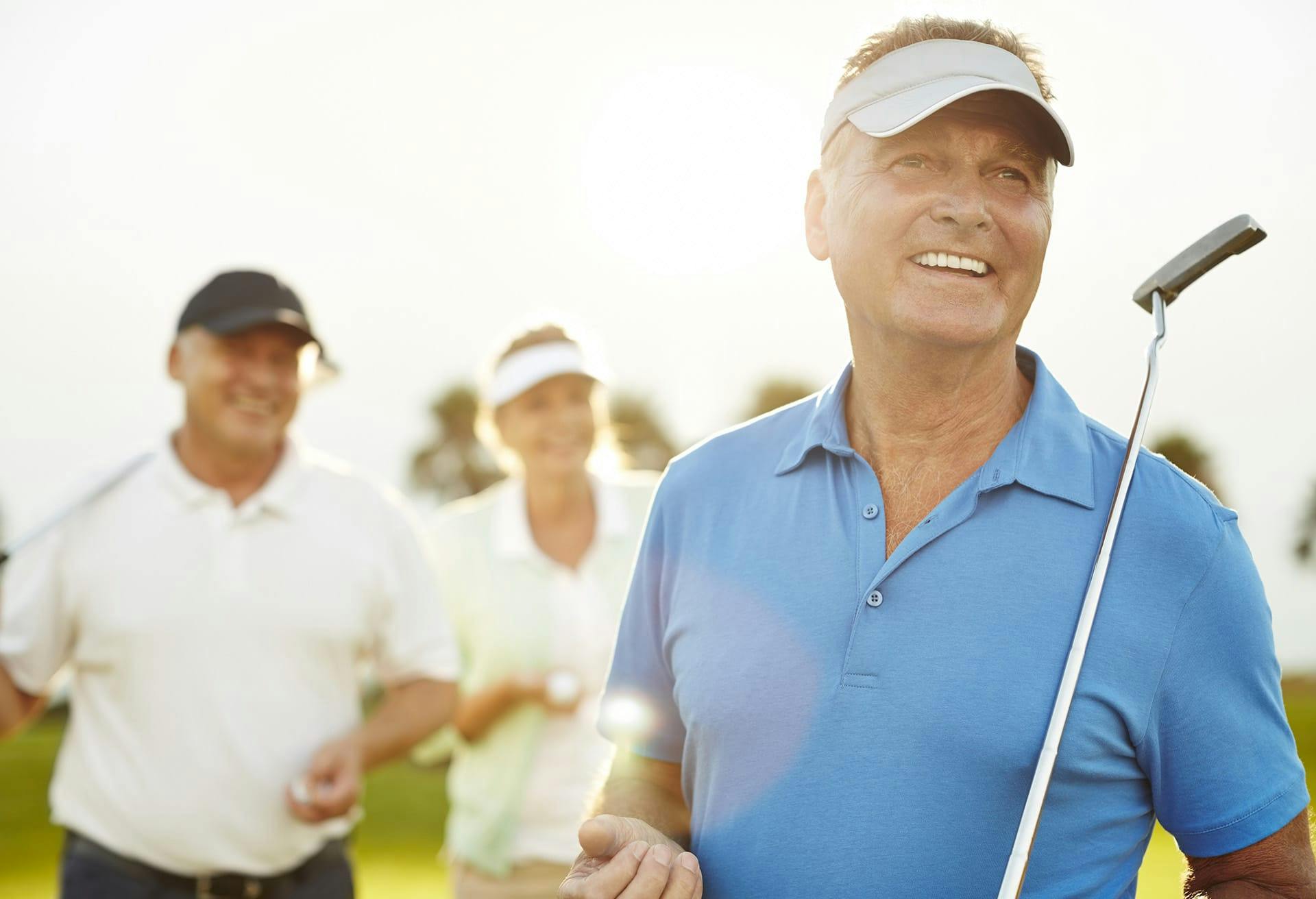 Three people holding golf clubs