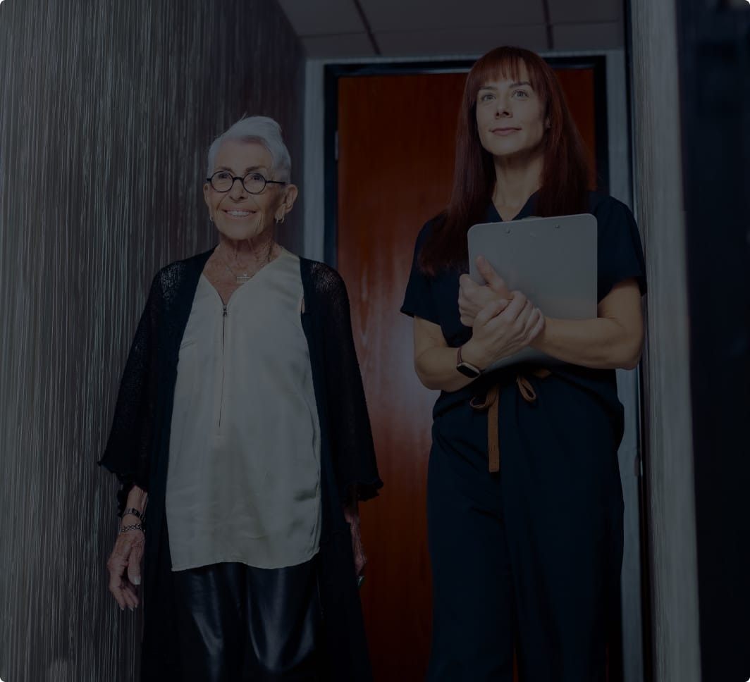 A staff member walking with an edlerly patient