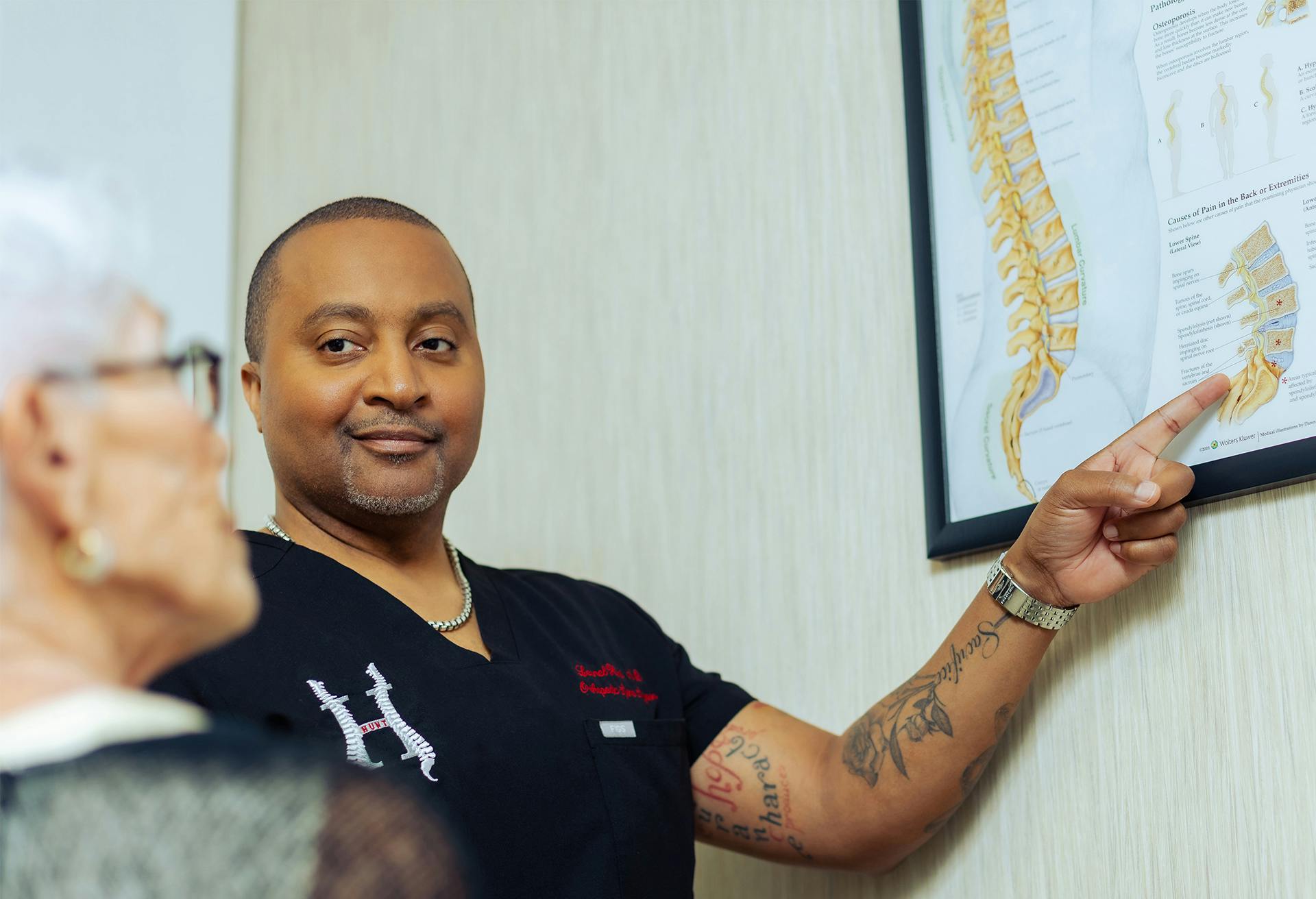 Dr. Leonel Hunt showing a patient a diagram of the spine, zoomed in