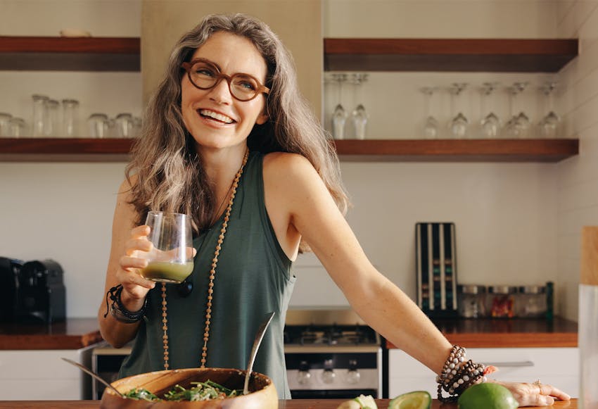 Woman with a glass, making food in her kitchen