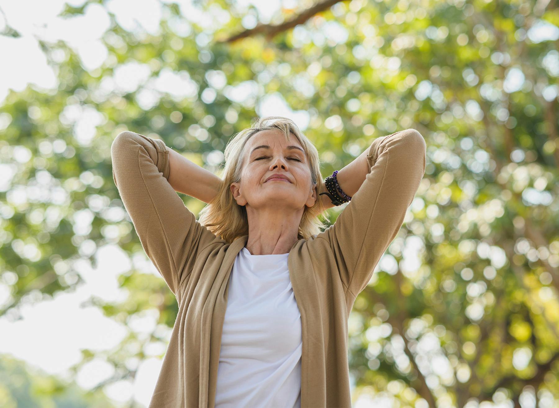 Woman closing her eyes with her arms behind her head