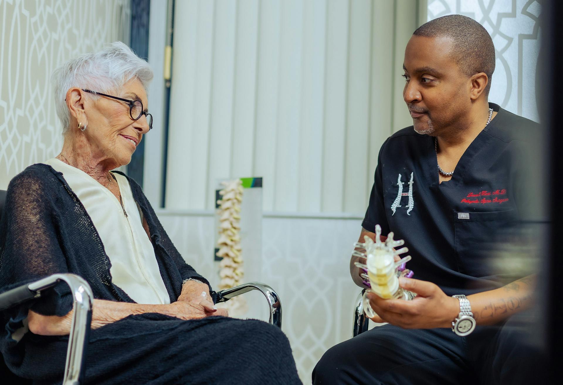 Dr. Leonel Hunt showing a patient a replica of a spine