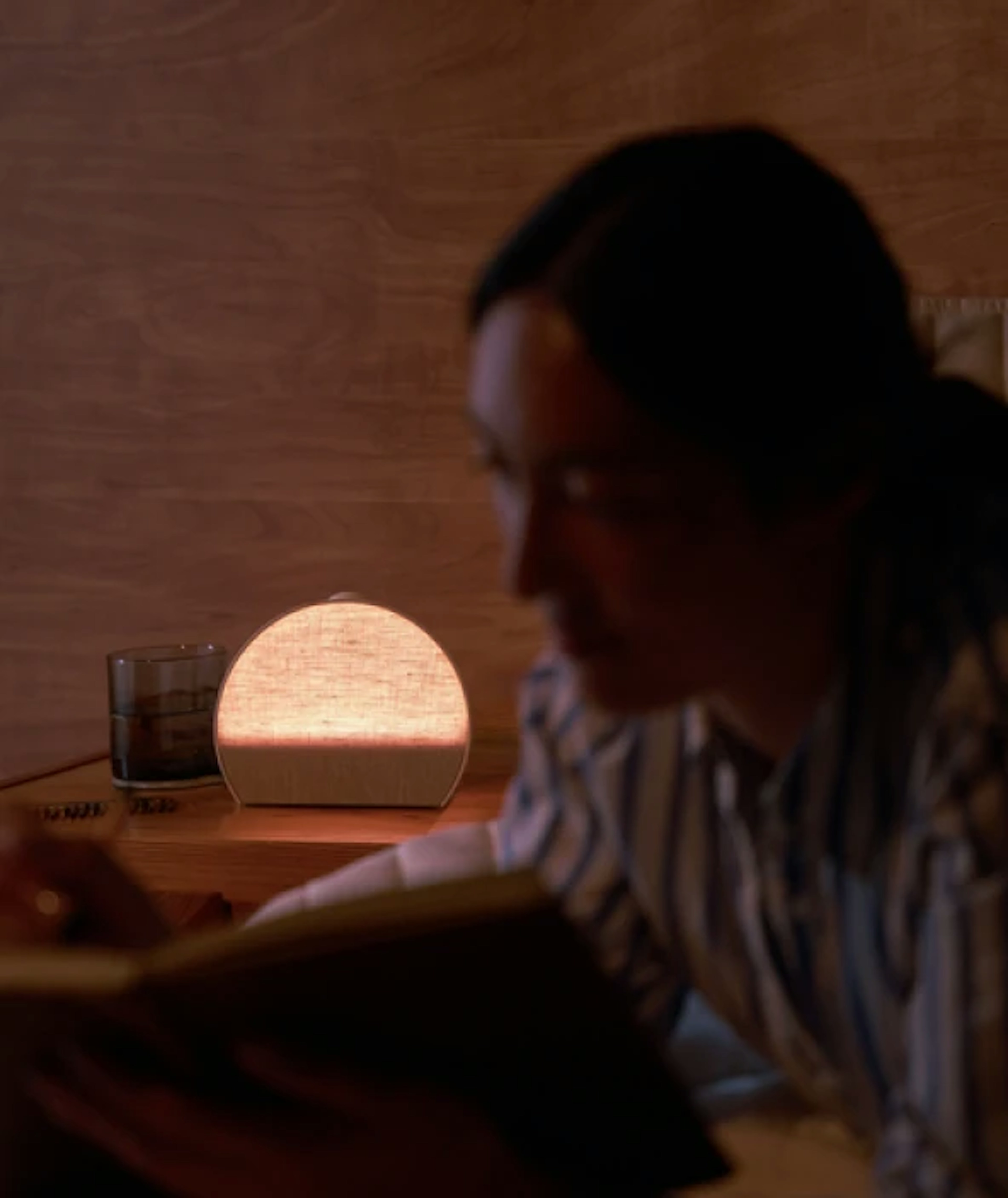 Unwinding with a book beside a softly glowing Hatch Sleep Clock