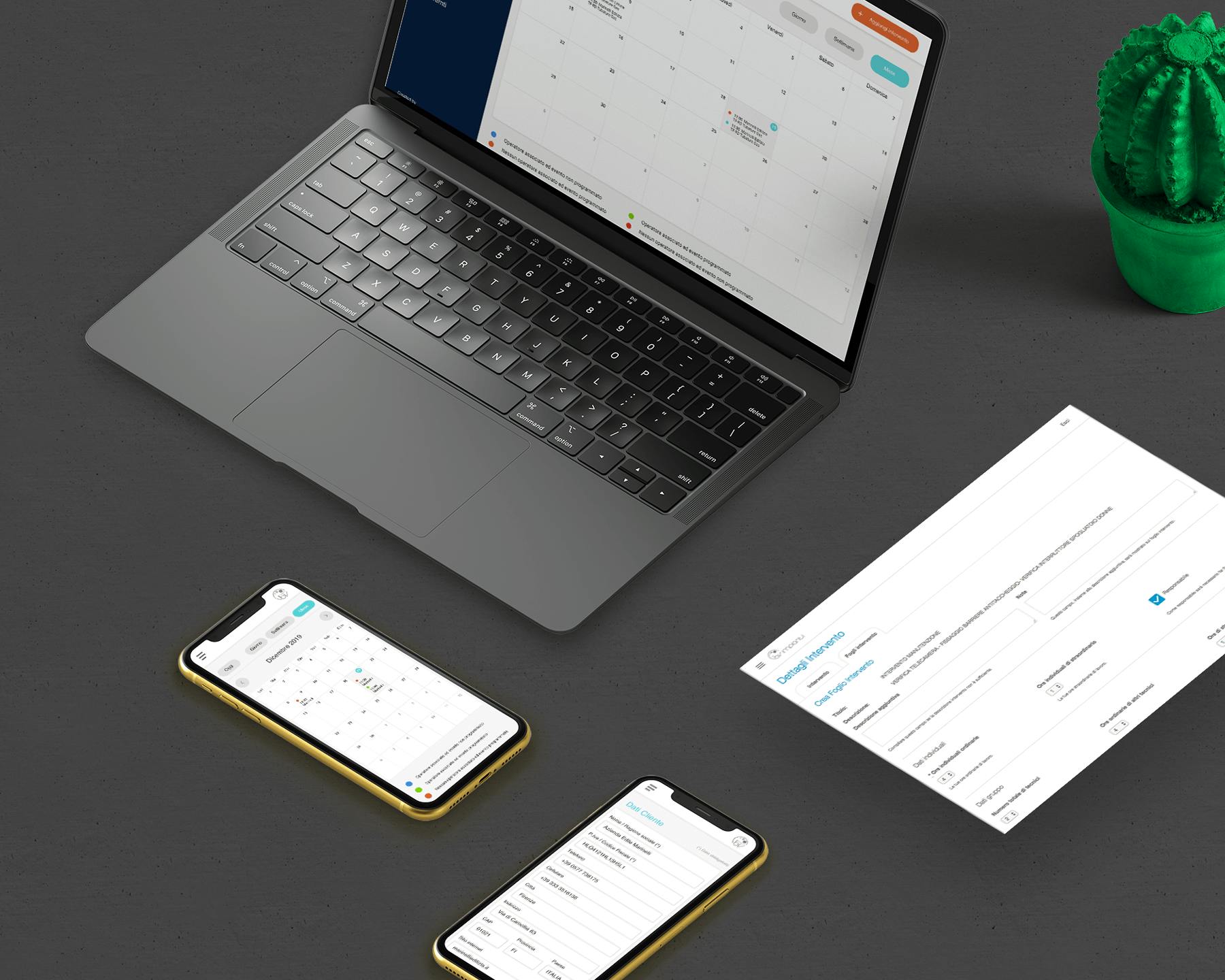 Un laptop aperto mostra un calendario sullo schermo, affiancato da due smartphone con display simili e un foglio di documenti su un tavolo scuro, con un piccolo cactus verde come decorazione.