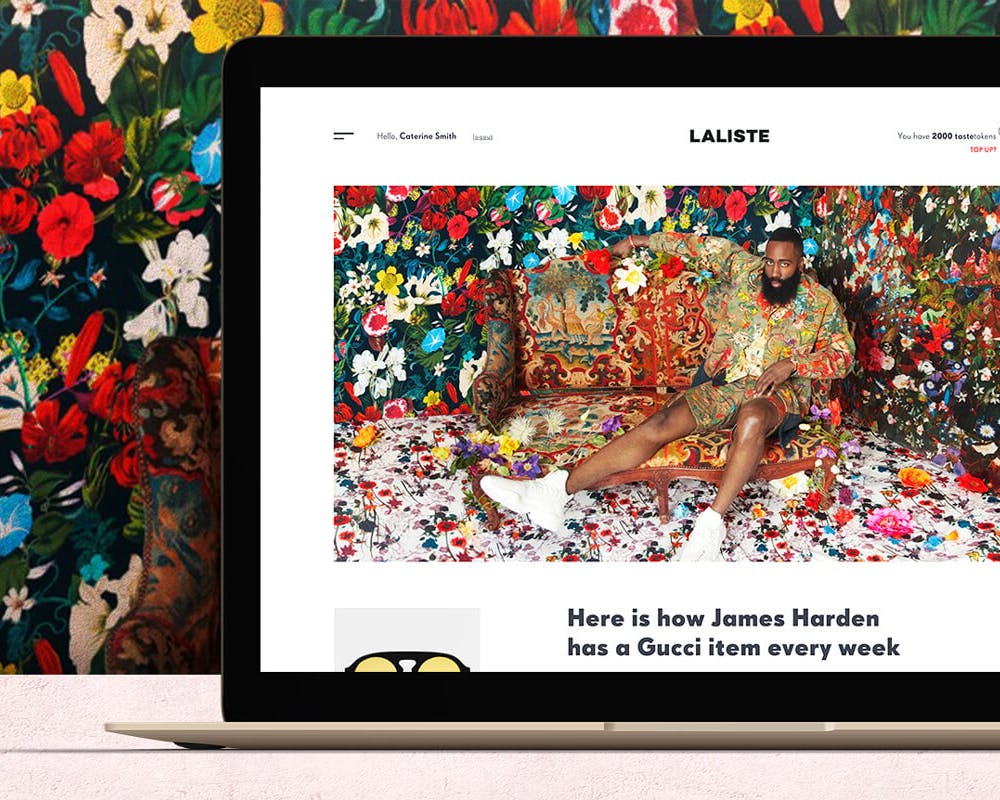 Un computer portatile è posizionato su un tavolo con lo schermo che mostra un sito web dai colori vivaci, mentre sullo sfondo un'elaborata carta da parati floreale aggiunge un tocco artistico e colorato all'immagine.