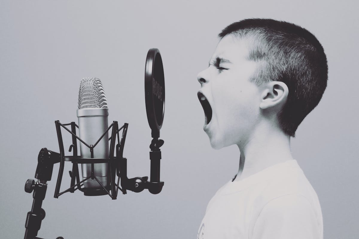 foto in bianco e nero di un bambino che apre la bocca verso un microfono professionale