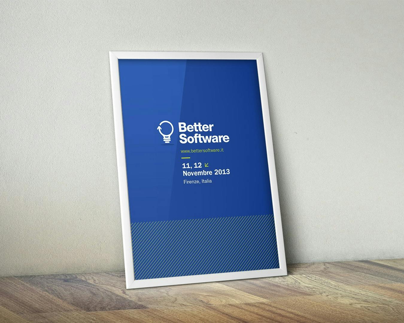 Una cornice bianca con un poster blu all'interno mostra informazioni sull'evento "Better Software" tenuto l'11 e 12 novembre 2013 a Firenze, Italia, collocato su un pavimento di legno contro un muro bianco.