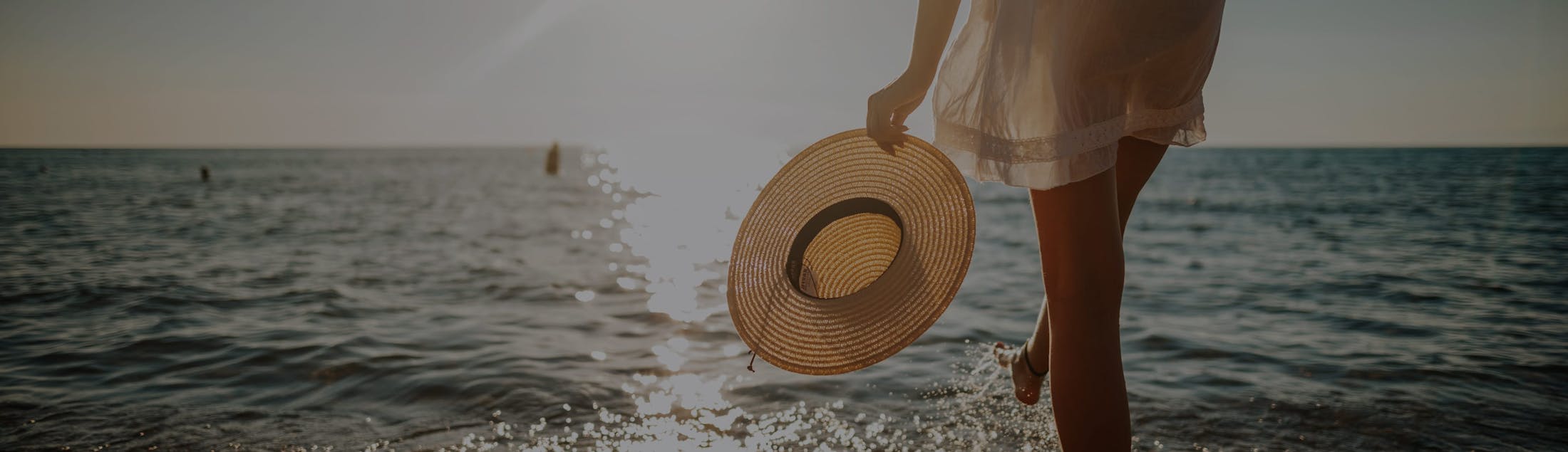 Woman holding a hat in her hand while walking in the ocean