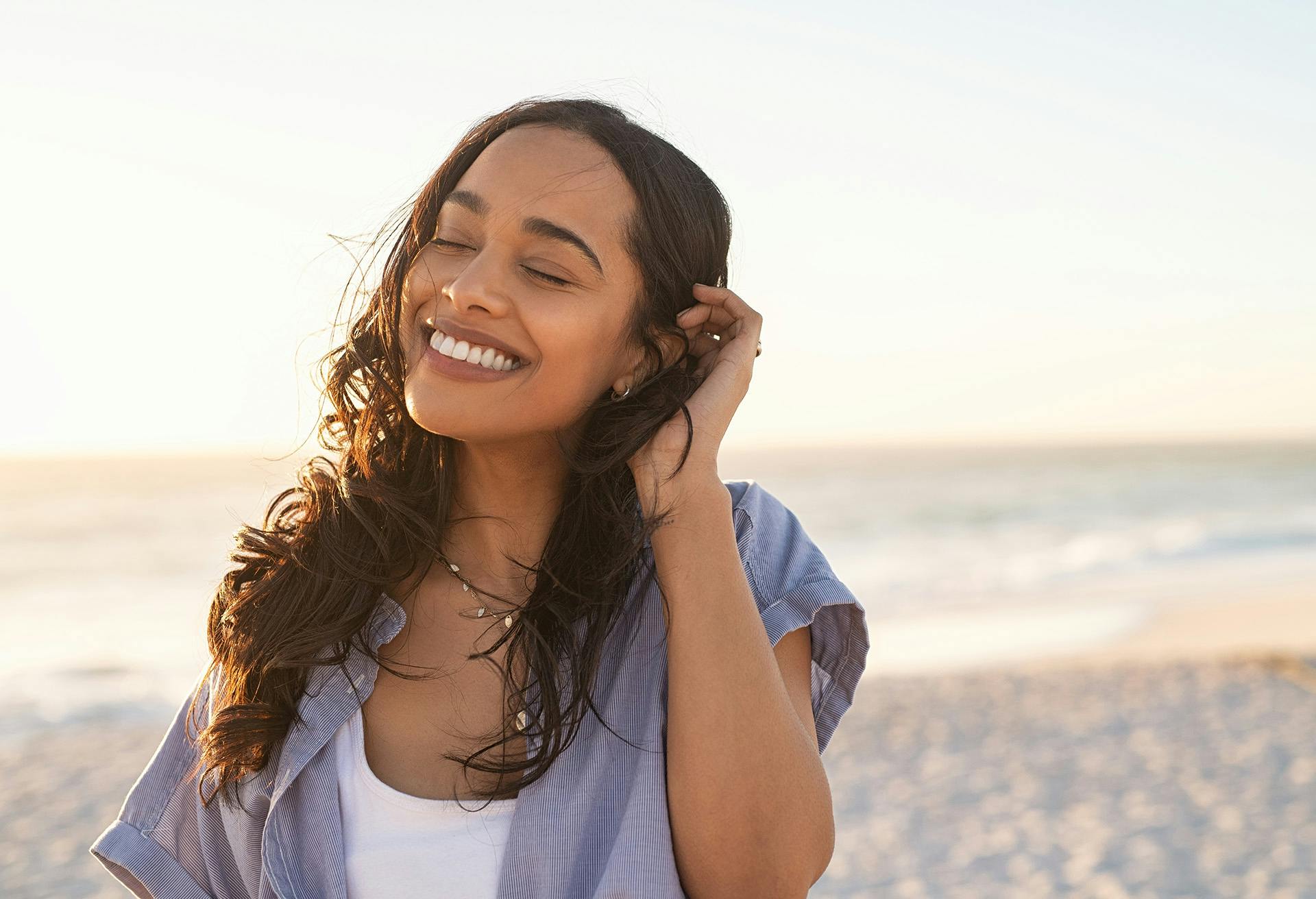 Woman smiling with her eyes closed at the beach