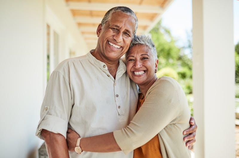 Older couple smiling while hugging eachother from the side