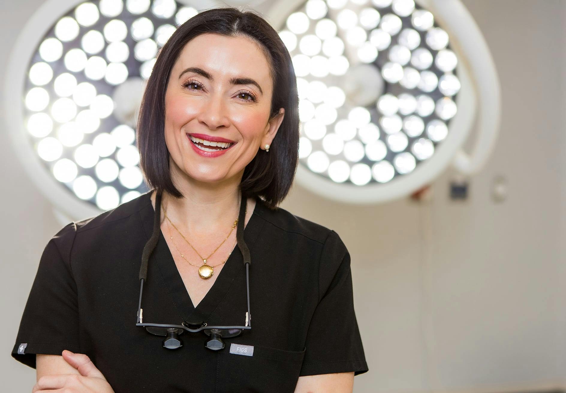 Dr. Helen Moses in black scrubs in front of operating lights