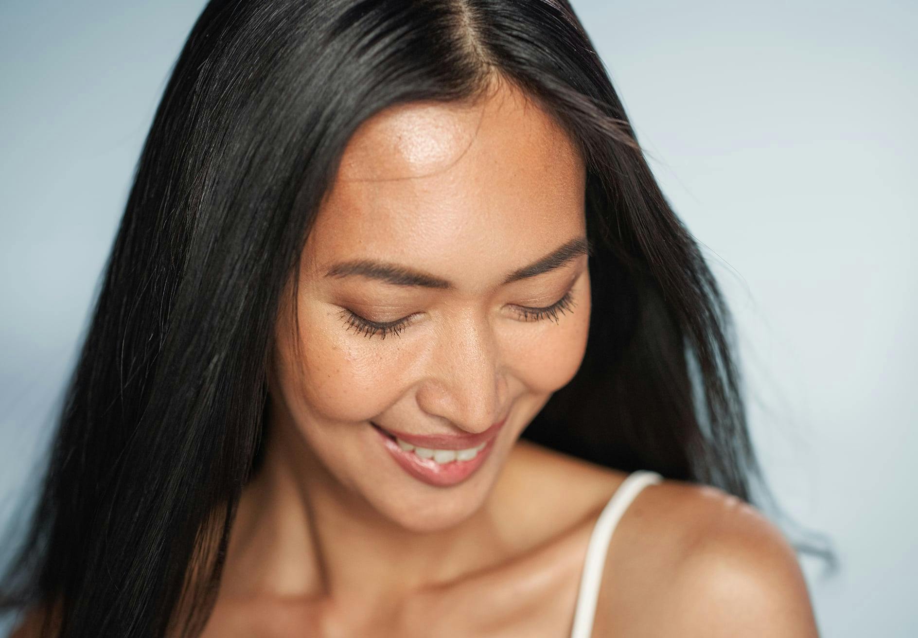 smiling woman with long black hair looking down while posing for picture