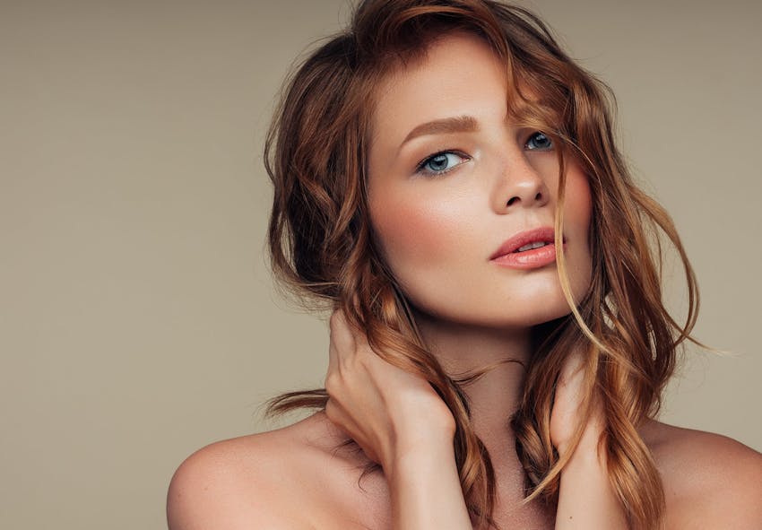 woman with long red hair and blue eyes posing for a picture with hands on neck