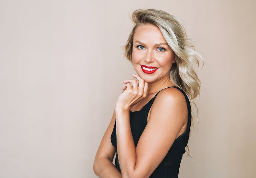 blond woman with red lipstick posing for a portrait in a black dress