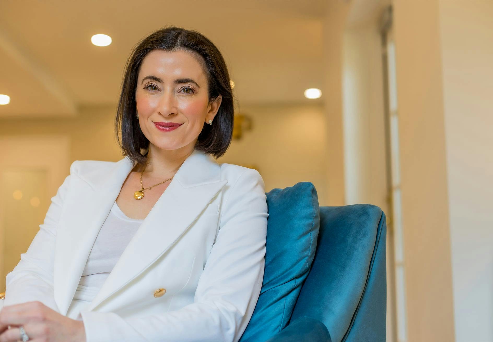 Dr. Helen Moses posing for photo in chair with white blazer and shirt