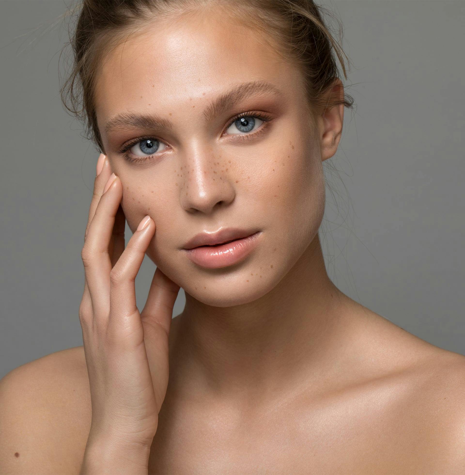 there is a woman with freckles touching her face