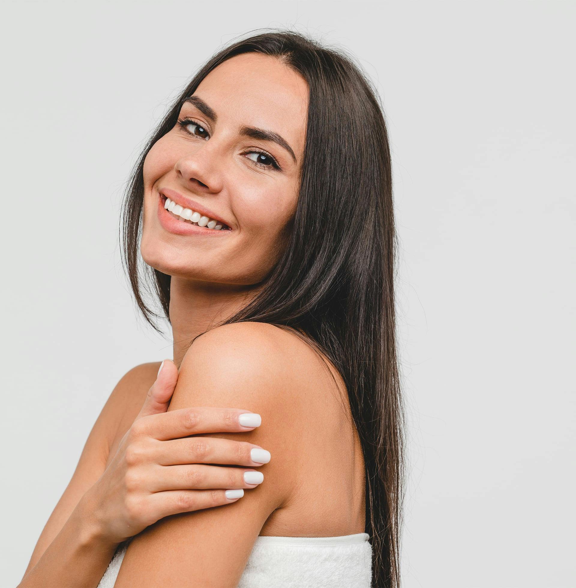 smiling woman with long dark hair and white towel wrapped around her waist