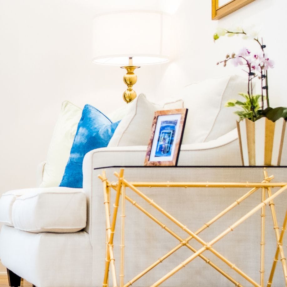 white couch with a gold frame table and a picture on it