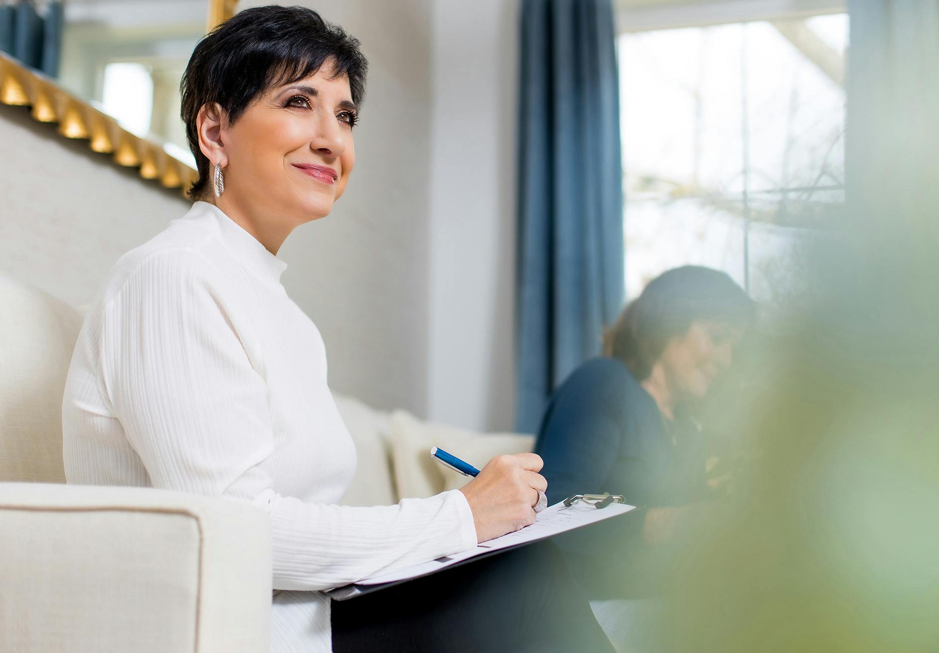 woman sitting on a couch with a notepad and pen in her hand