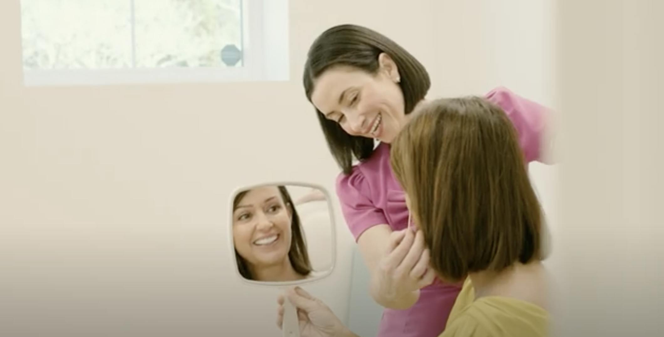 Dr. Helen Moses helping a patient look at herself in a mirror while smiling