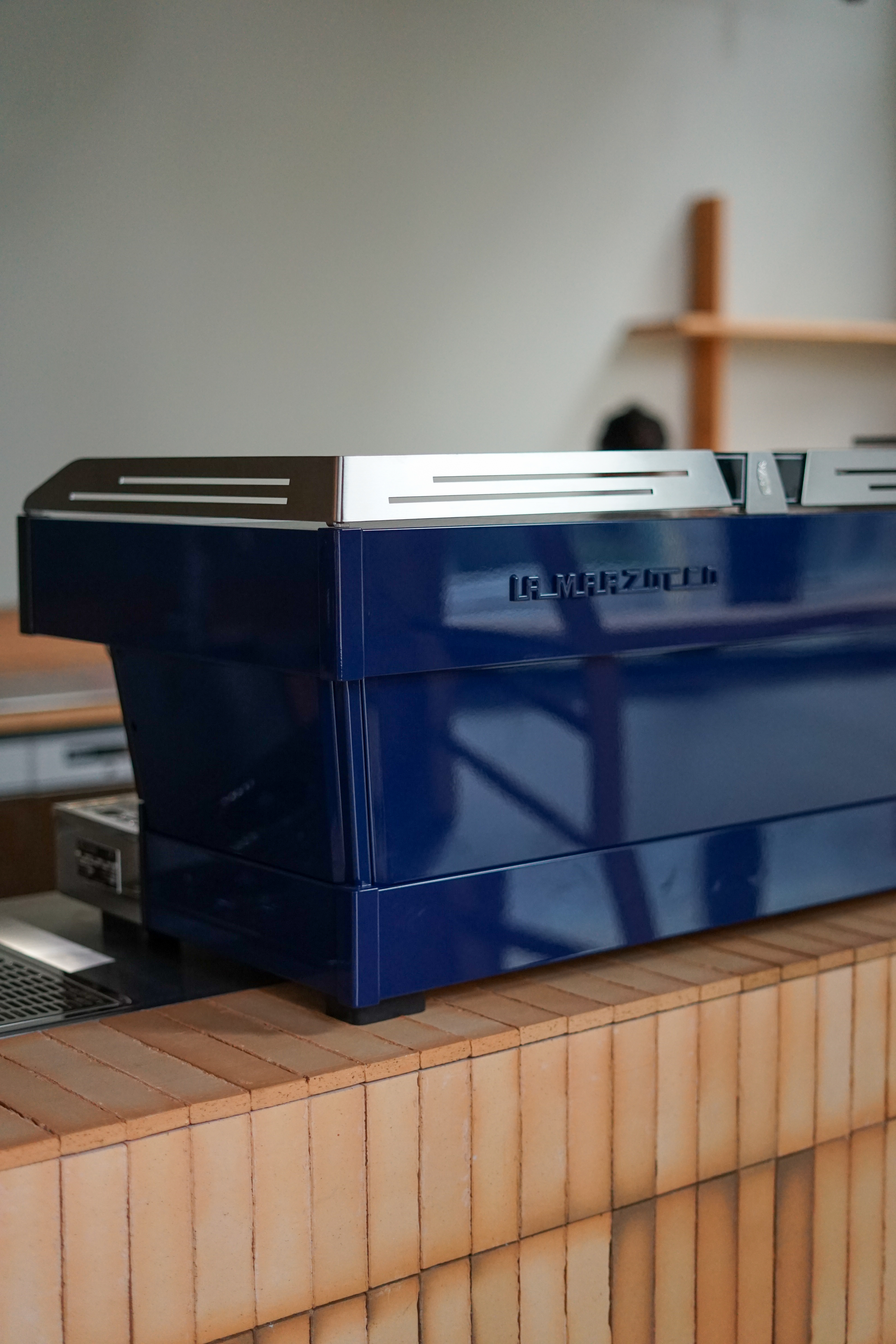 The blue La Marzocco machine beautifully stands out in a room full of light natural materials