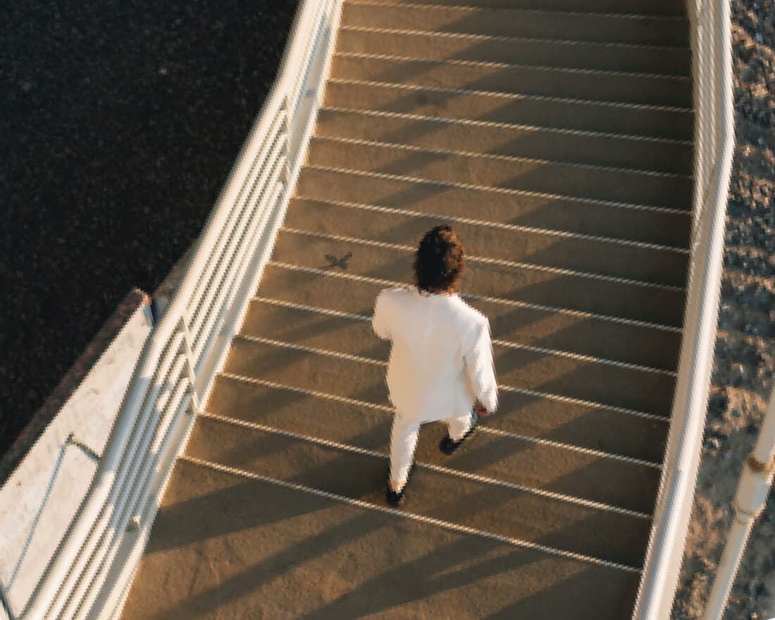 Un uomo in completo bianco scende le scale