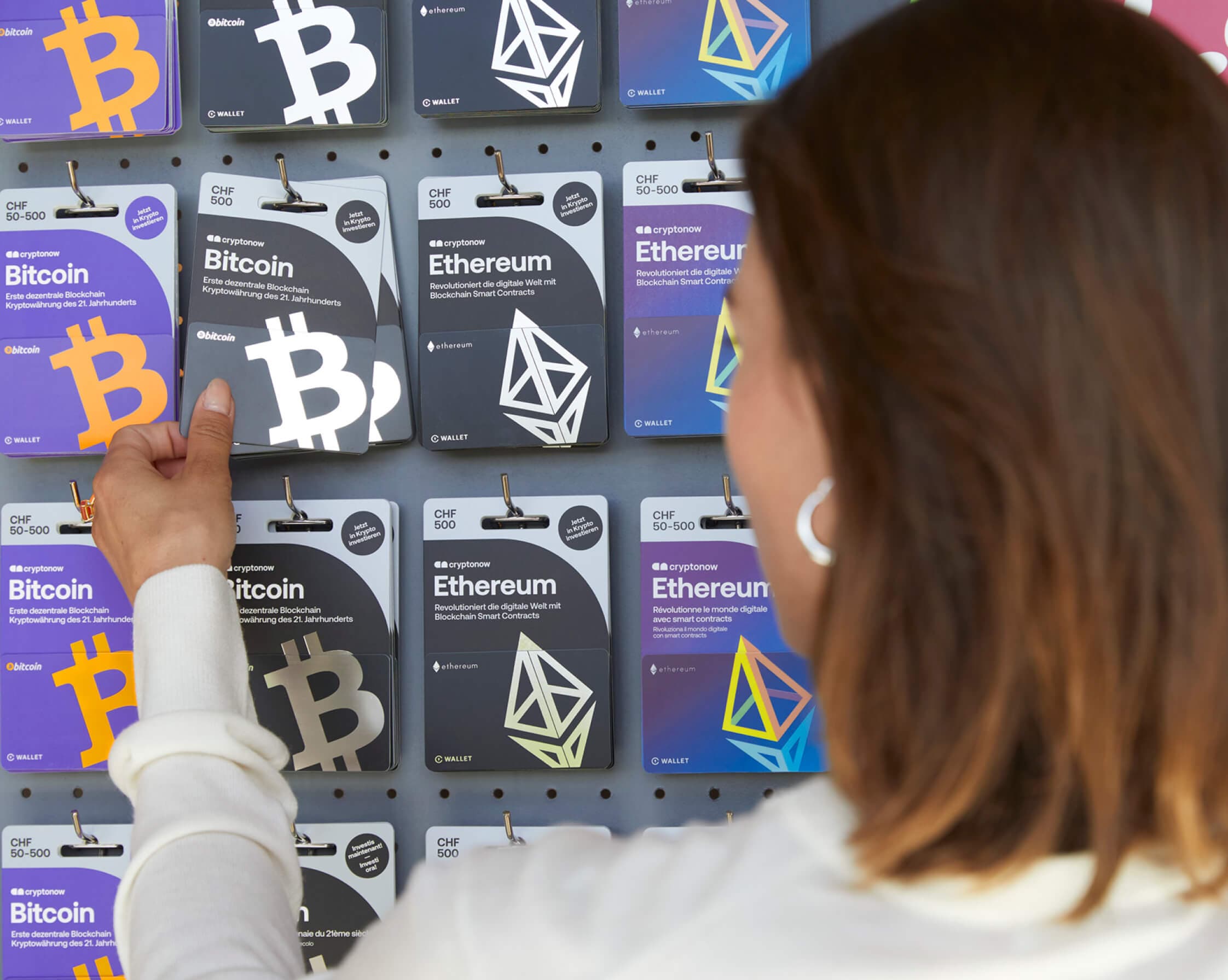 A woman selects a Cryptonow card in the store