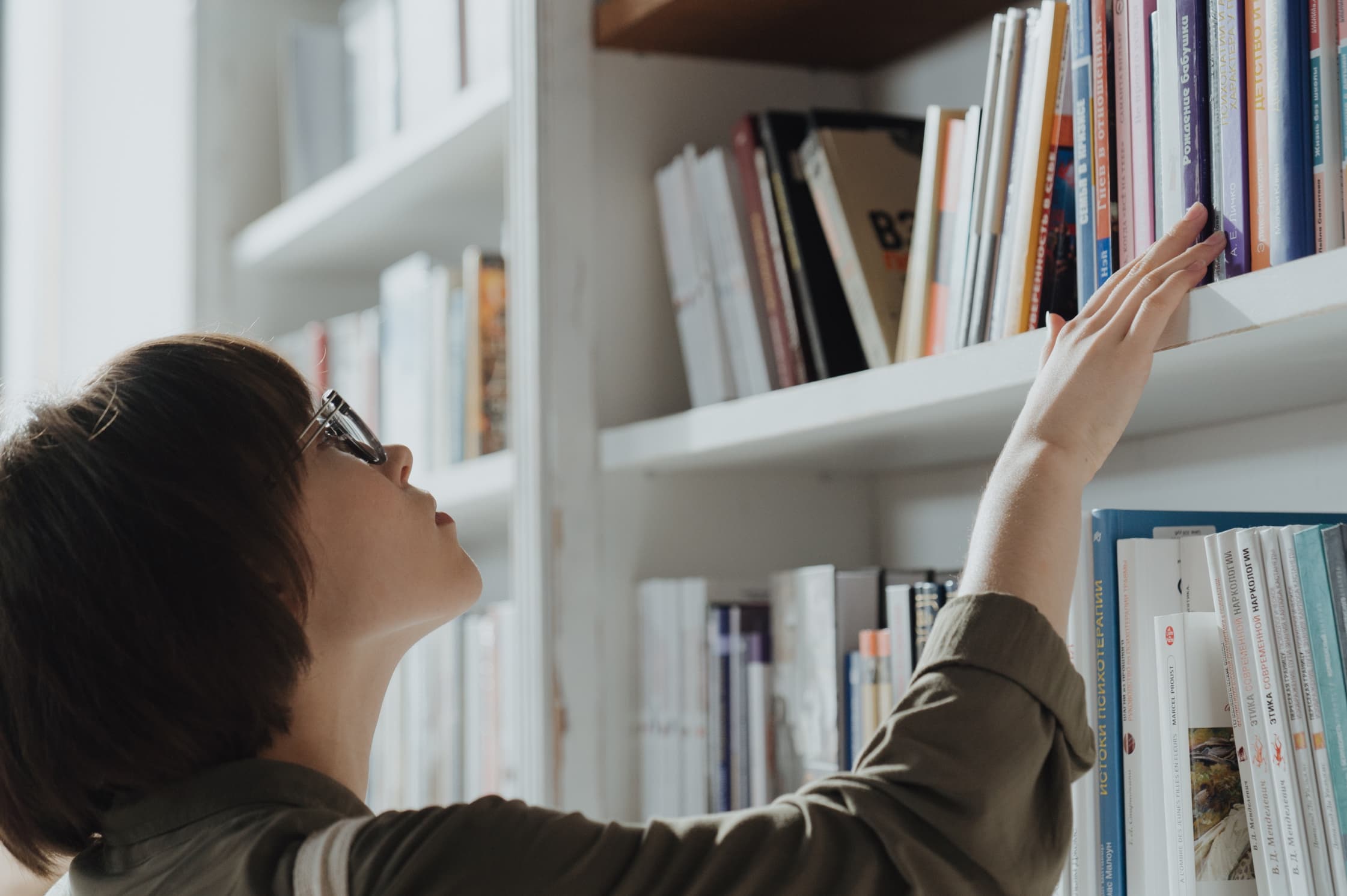 A woman selecting a book to further educate herself about crypto