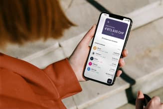 Una persona tiene un iPhone y sigue los precios de las criptomonedas en la aplicación de billetera.