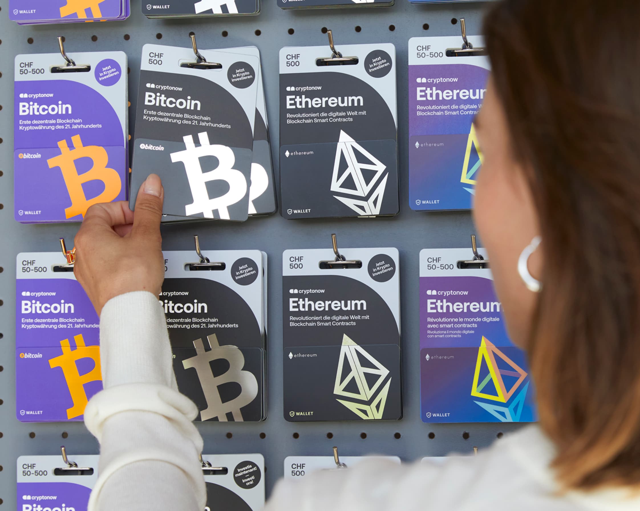 Eine Frau sucht sich im Laden eine Cryptonow Karte aus