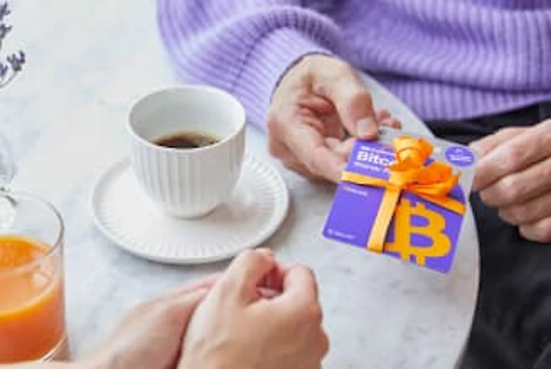 Una persona sta regalando a un'altra una carta regalo Cryptonow confezionata