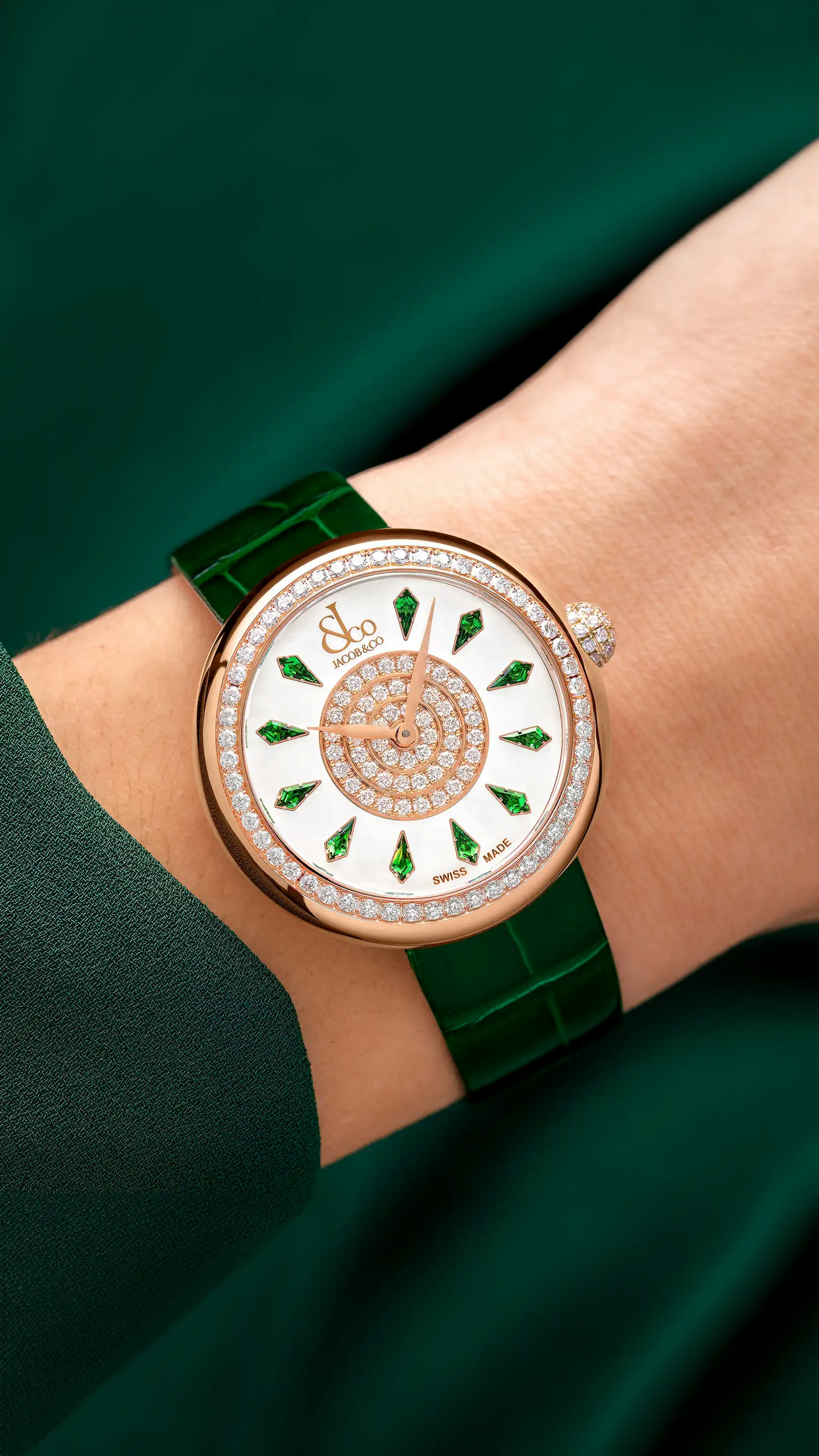 The rose gold, tsavorite Brilliant Watch, with tsavorite hour markers. Worn on the left wrist.