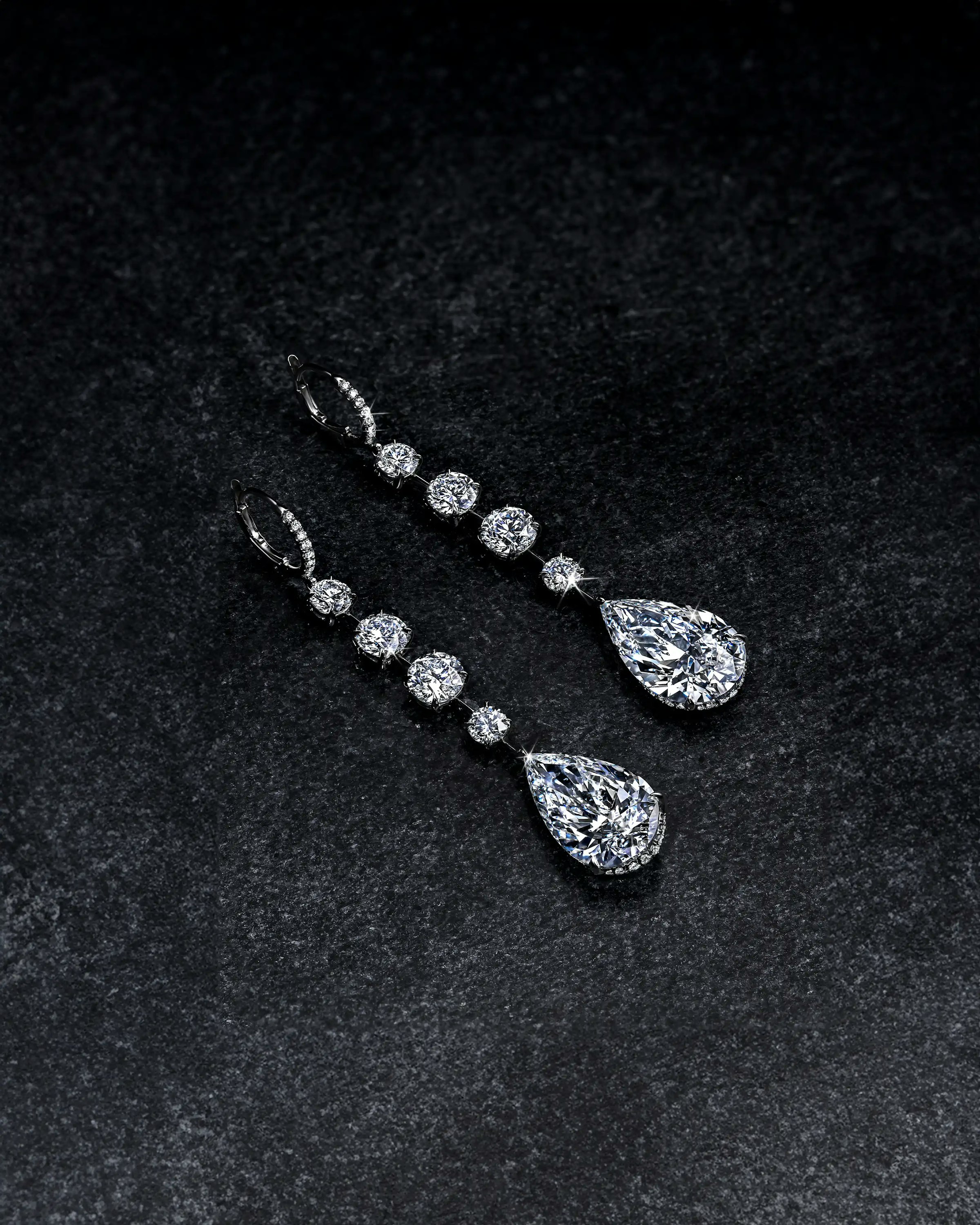 the white diamond teardrop earrings, laid flat on a surface.