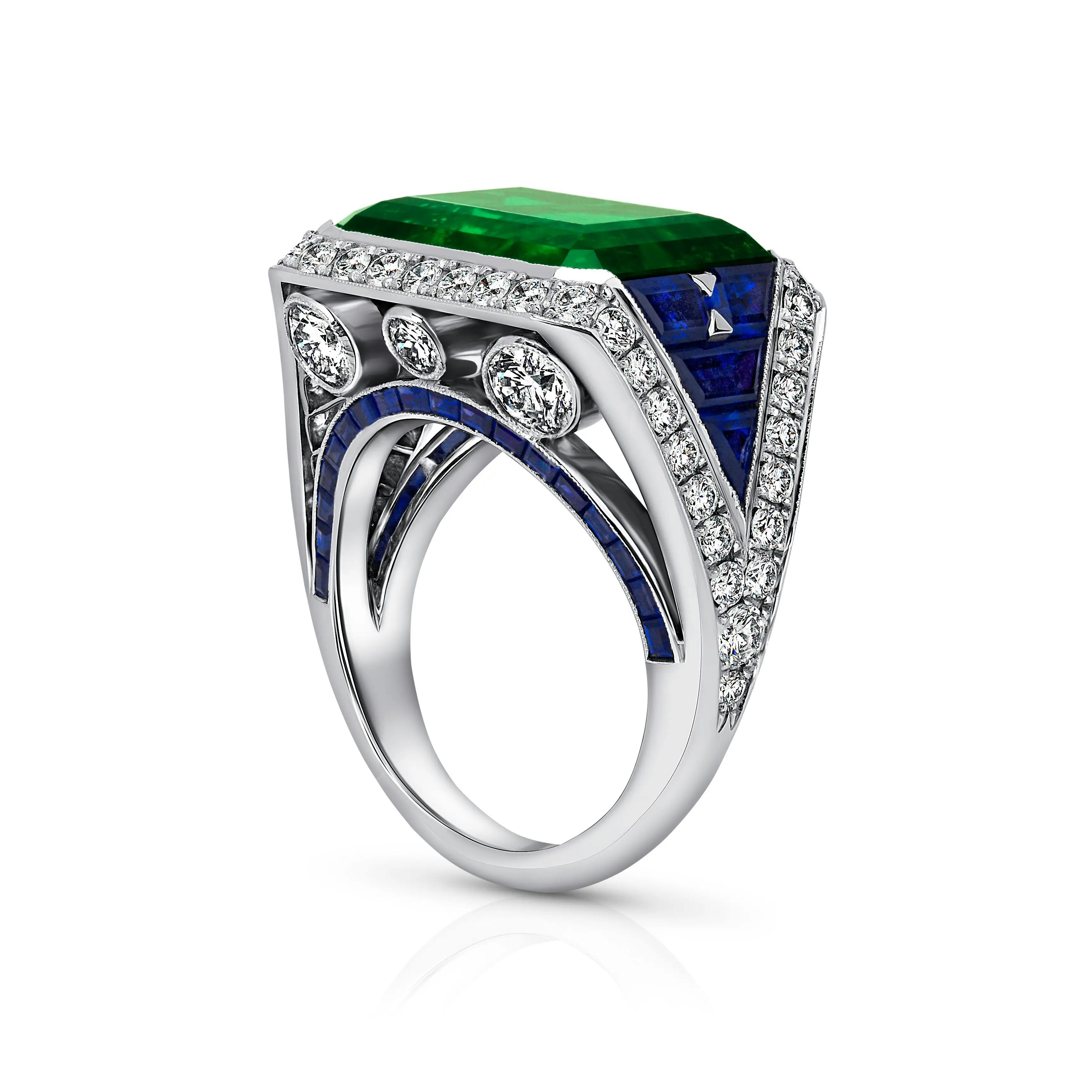 the eye of the emerald ring, positioned upright, facing the viewer 3/4 of the way to show the diamond and sapphire setting.